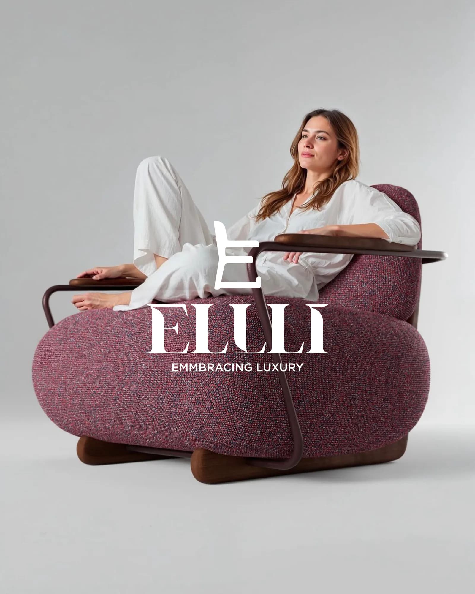 Campaign frame of a model seated on a plum bouclé sofa beside the Ellli monogram