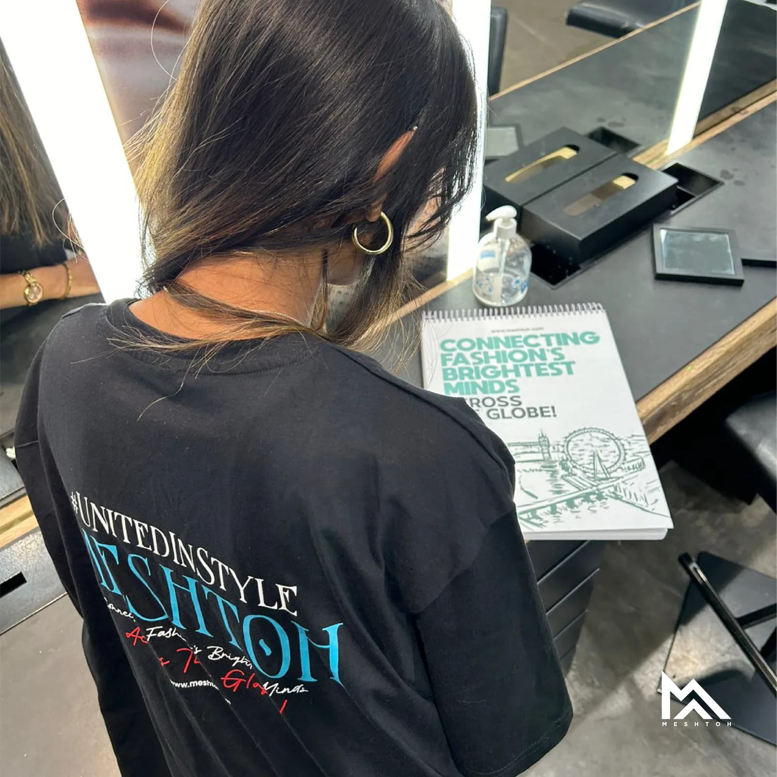 Branded tee photographed from behind at a workspace